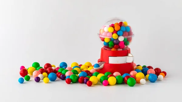 A plastic toy gum ball machine filled and surrounded by gum balls. — Stock Photo, Image