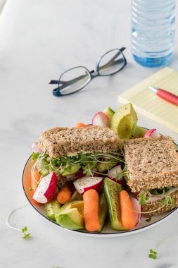 Çiğ sebzelerle servis edilen sağlıklı bir pelerin tohumu ekmek sandviçi..