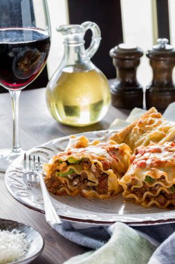 Ev yapımı lazanya ruloları akşam yemeği için kırmızı şarap ve sarımsaklı tost ile servis edilir.