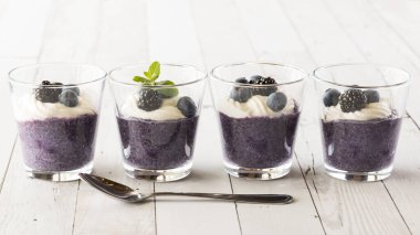 Önünde kaşık olan bir sıra sağlıklı yaban mersinli puding.. 