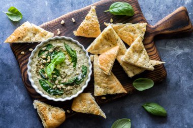 Pesto Humus 'un yukarıdan aşağı görünüşü, pide üçgenleriyle servis ediliyor, daldırmaya hazır..