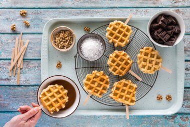 Çikolata, fındık ve tuzlu karamel de dahil olmak üzere çeşitli malzemelerle dekore etmeye hazır bir sürü waffle çubuğu var..