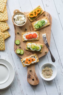 Kraker ve taze malzemelerle dolu, yenmeye hazır ahşap bir tahtanın yukarıdan görünüşü..