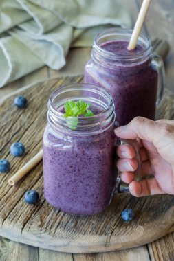 Elinde bir kavanoz ev yapımı taze ve kremalı yaban mersini püresi, arkasında da bir tane.. 