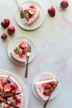 Top down view of slices of homemade strawberry cheesecake with copy space to the right. 