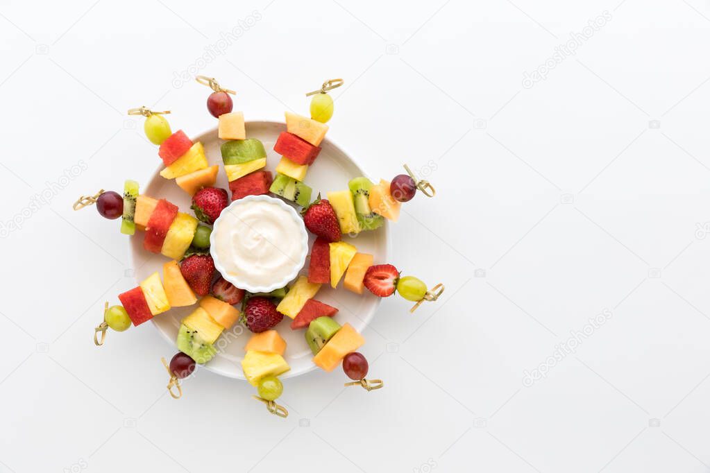 A tray of bright colourful fresh fruit skewers isolated against a white background. 
