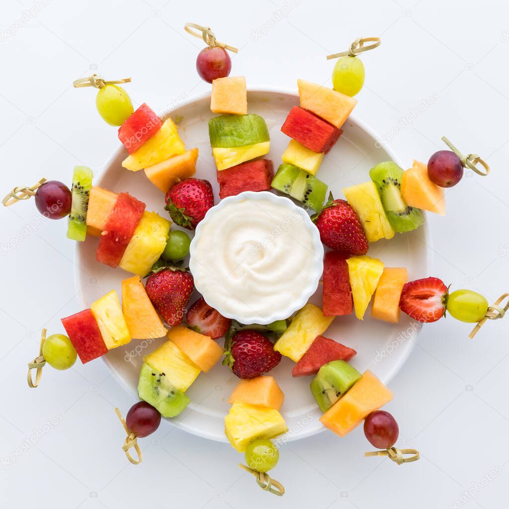 A platter of fresh fruit skewers isolated against a white background. Square crop.