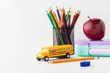 Back to school supplies including pencil crayons, lunchbox and apple with copy space to the left.