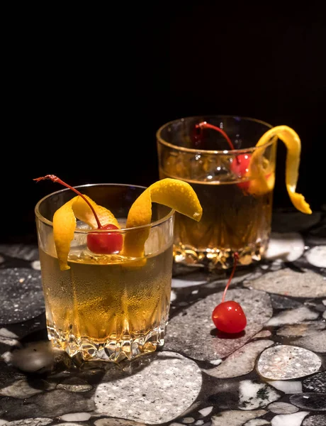 Two refreshing Old Fashioned cocktails against a black background.