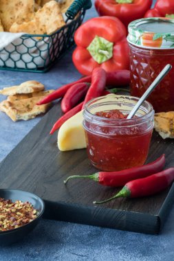 Biber, kraker ve peynirle çevrili ev yapımı sıcak biber jölesi kavanozları.. 