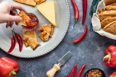 Bir el, çıtır kraker ekmeğini ev yapımı sıcak biber jölesine batırıyor..