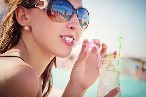 Young woman with a cocktail in the swimming pool — Stock Photo, Image