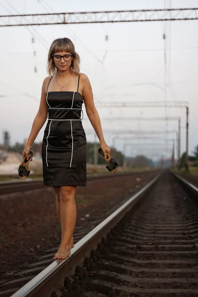 Jeune belle fille avec des lunettes sur le fond du chemin de fer . — Photo