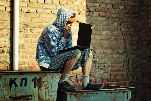 genç bir adam Çöp konteyner üzerinde oturan laptop ile çalışma