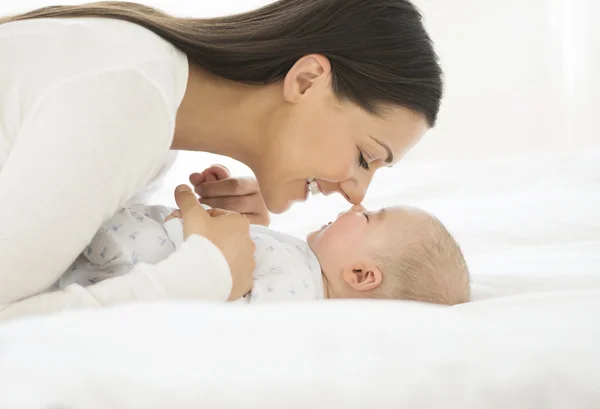 Küçük bebek yatakta ile oynayan kadın — Stok fotoğraf