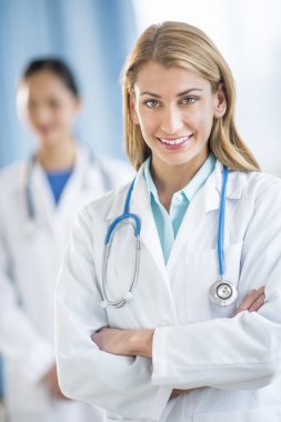 mutlu kadın doktor ayakta kolları klinikte çarpı işareti.
