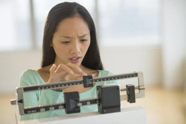 Vrouw aanpassen evenwicht gewicht schaalbereik bij gym — Stockfoto