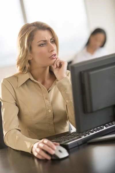 Empresaria confusa usando computadora en el escritorio en la oficina — Foto de Stock