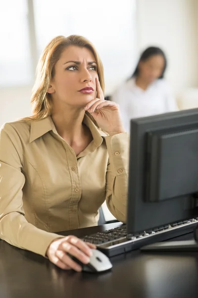 Nachdenkliche Geschäftsfrau nutzt Computer am Schreibtisch — Stockfoto