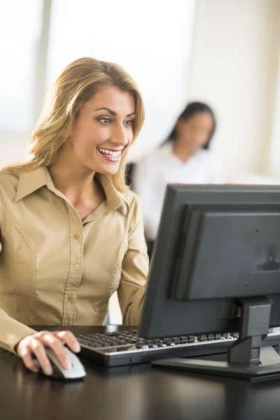 Feliz mujer de negocios utilizando la computadora en el escritorio en la oficina —  Fotos de Stock