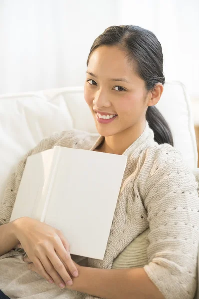 Femme avec livre se détendre sur le canapé à la maison — Photo