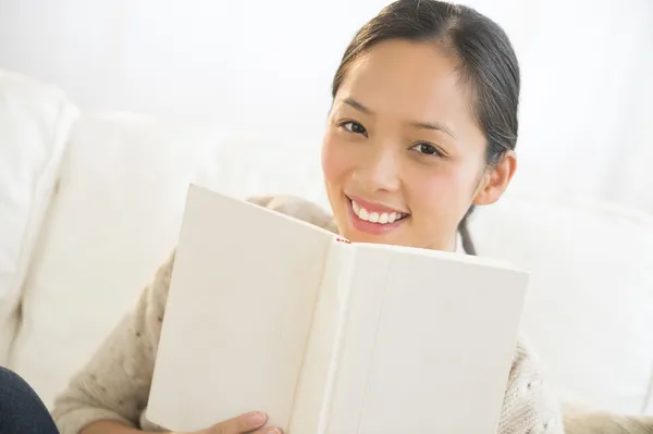 Mujer feliz con libro sentado en el sofá —  Fotos de Stock