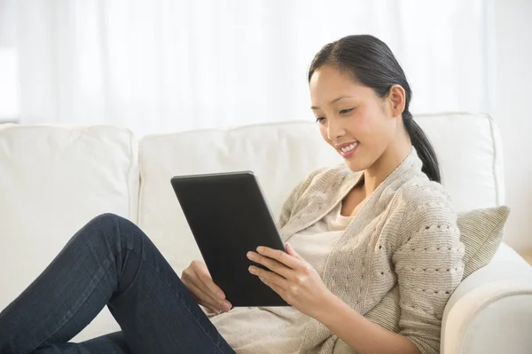 Vacker kvinna med digital tablet medan du kopplar av på soffan — Stockfoto