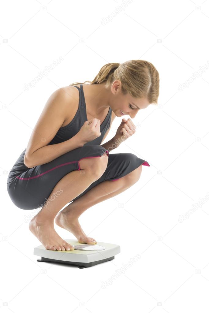 Excited Woman Weighing Herself On Weight Scale
