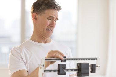 endişeli erkek spor salonunda ağırlık ölçeği kullanarak