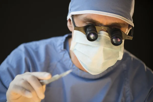 Cirujano usar máscara y lupa gafas celebración de bisturí — Foto de Stock