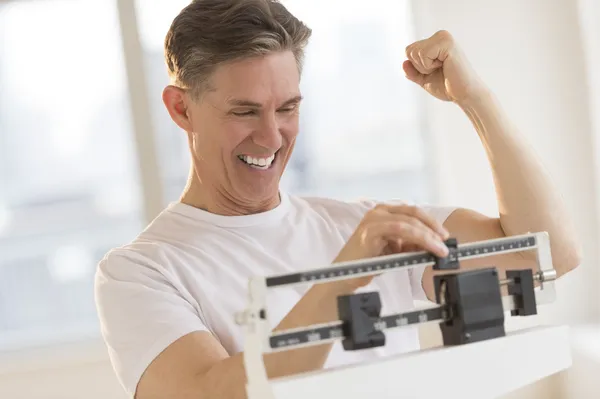 Izgatott férfi összeszorítása ököl kilogramm skála használata közben — Stock Fotó