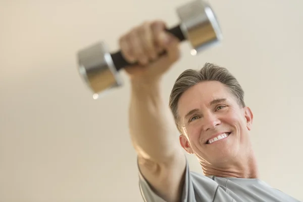 Happy Man Lifting Dumbbell Against Beige Background — Stock Photo, Image