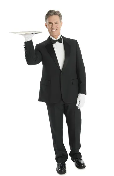 Retrato de camarero confiado llevando bandeja sobre fondo blanco — Foto de Stock
