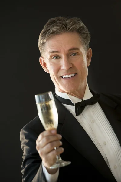 Šťastný muž ve smokingu opékání šampaňské flétna — Stock fotografie