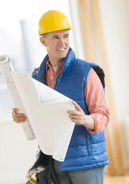 Architect Looking Away While Holding Blueprint At Construction S — Stock Photo, Image