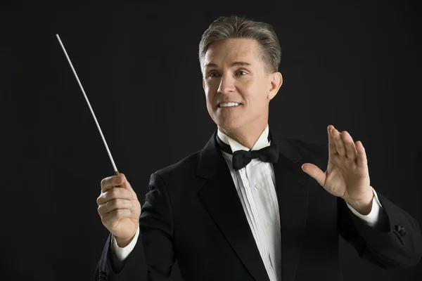 Maestro de orquestra olhando para longe enquanto dirige com seu bastão — Fotografia de Stock
