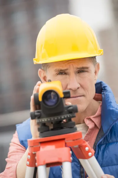 Säker mogna byggnadsarbetare med teodolit — Stockfoto