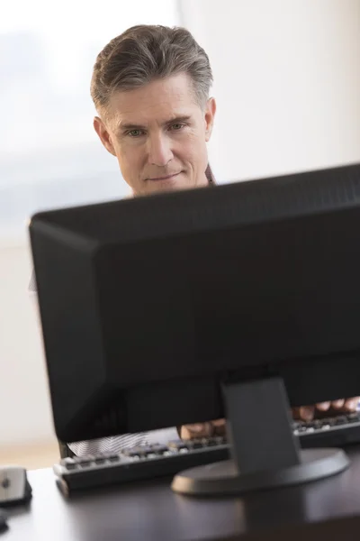 Empresario sonriendo mientras mira el monitor de computadora —  Fotos de Stock