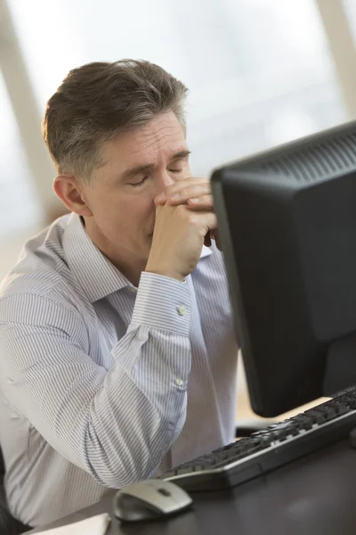 Uitgeput zakenman leunend op computerbureau — Stockfoto