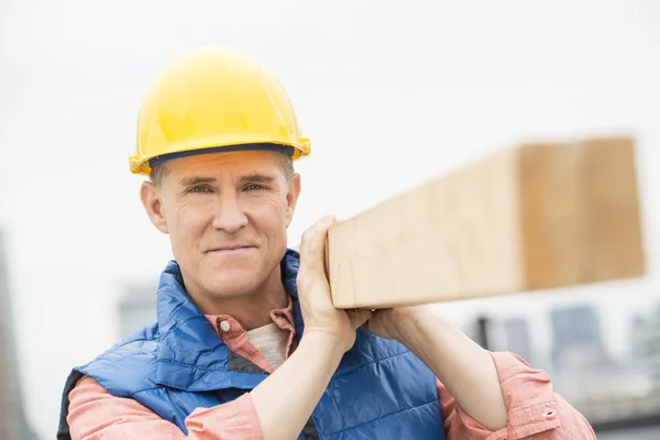 Ouvrier confiant portant une planche en bois — Photo