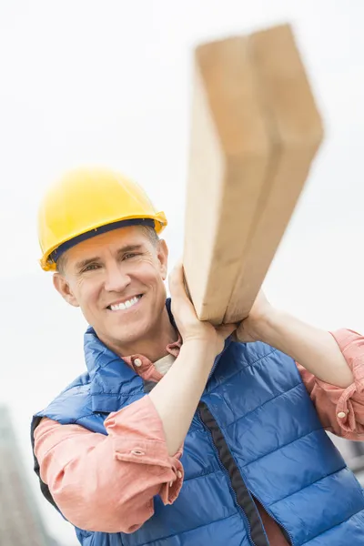 Travailleur de la construction heureux portant la planche en bois — Photo