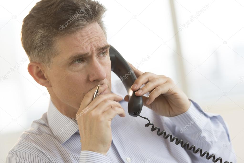 Thoughtful Businessman Using Landline Phone In Office