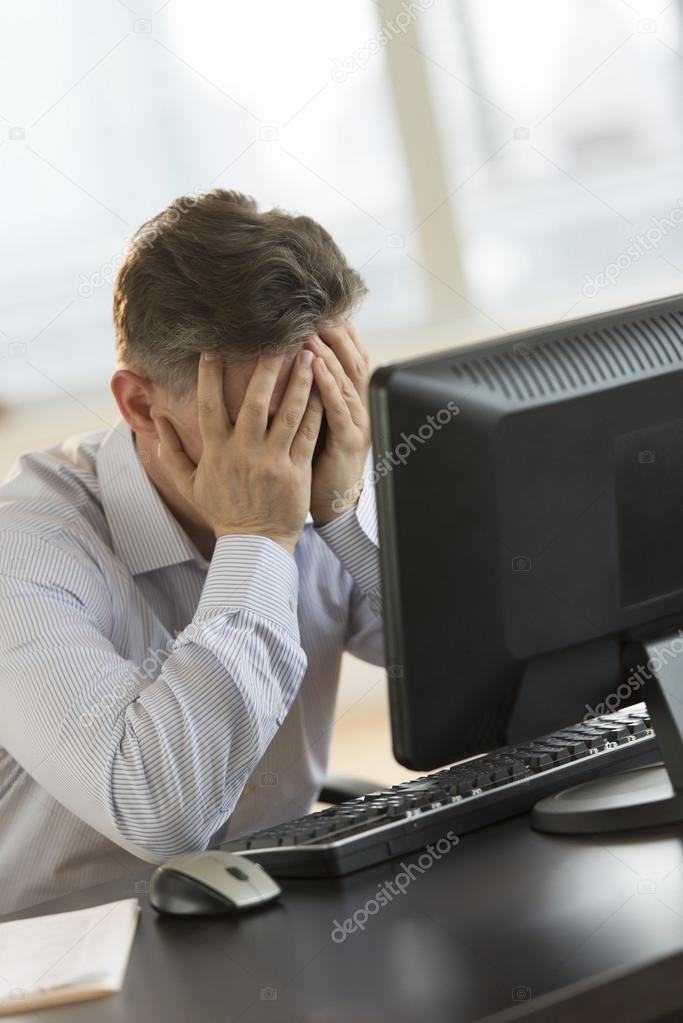 Tired Businessman Leaning On Computer Desk