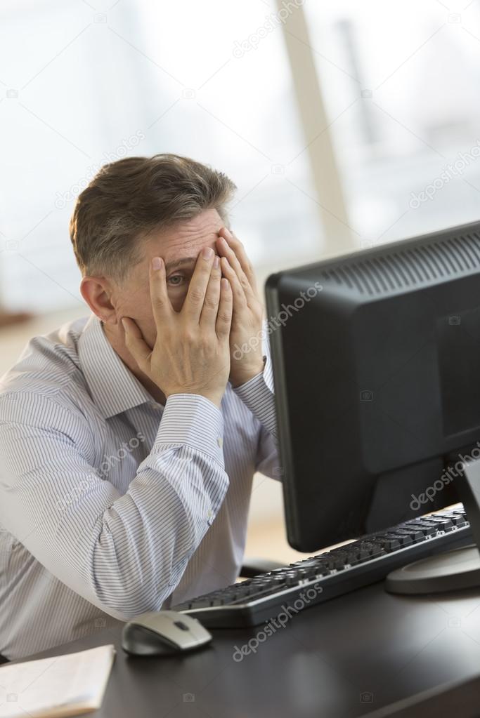 Frustrated Businessman With Hands On Face Looking At Computer