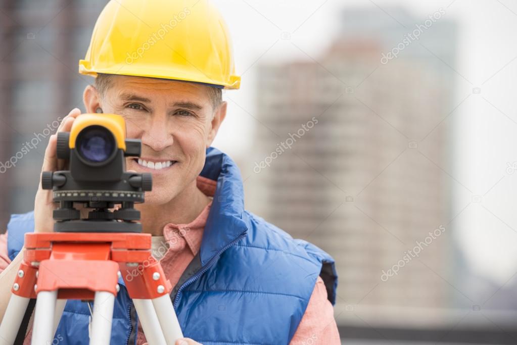 Happy Mature Construction Worker With Theodolite