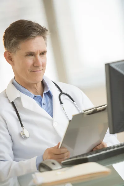 Médico sonriendo mientras mira la computadora —  Fotos de Stock