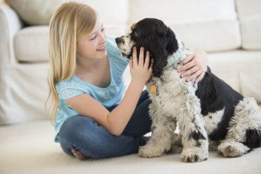 Girl Playing With Pet Dog In Living Room clipart