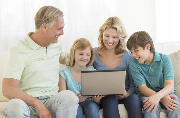 Pais e crianças usando laptop juntos no sofá — Fotografia de Stock