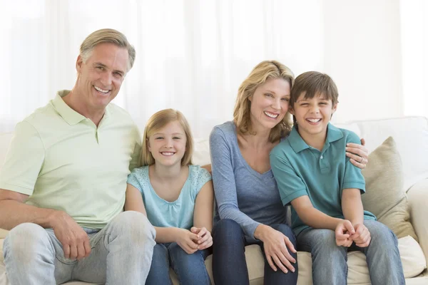 Familie van vier glimlachend samen op de Bank — Stockfoto