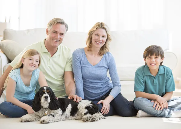 Rodina s psa sedět na podlaze v obývacím pokoji — Stock fotografie